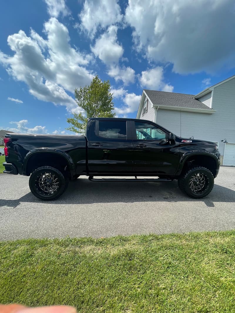 Black pickup truck with deep glossy paint and dressed tires after an exterior detail