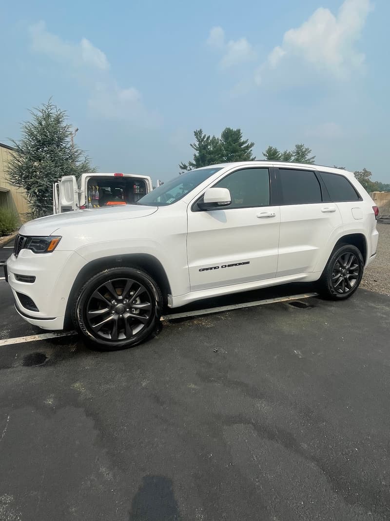 White Jeep Grand Cherokee with black wheels, freshly washed and dressed