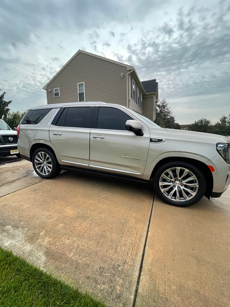 White full-size SUV with gleaming paint and clean wheels in a customer driveway